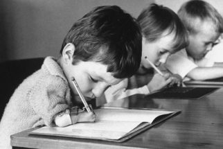 Niños con malformaciones en los brazos escribiendo.