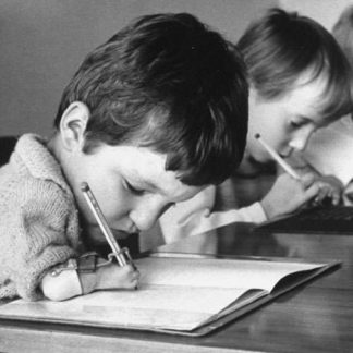 Niños con malformaciones en los brazos escribiendo.